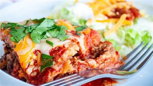 ломтик запеканки энчилада с вилкой на тарелке