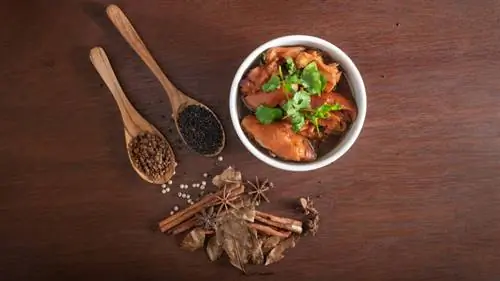 Чаша тушеного мяса с различными ингредиентами на деревянном столе Чаша тушеного мяса с различными ингредиентами на деревянном столе