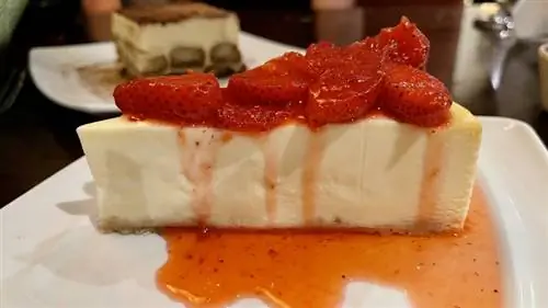 Ломтик клубничного чизкейка Olive Garden на тарелке с ягодами сверху