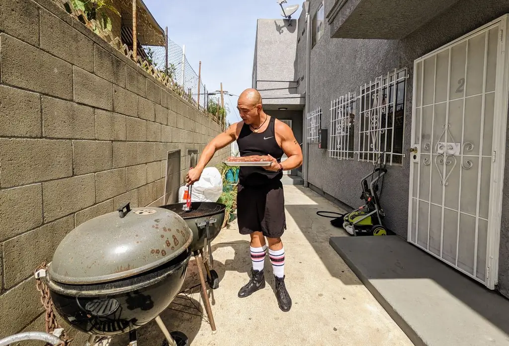 Джонерик Конкордия очищает решетку котла куском скомканной алюминиевой фольги, прежде чем положить приправленную говядину