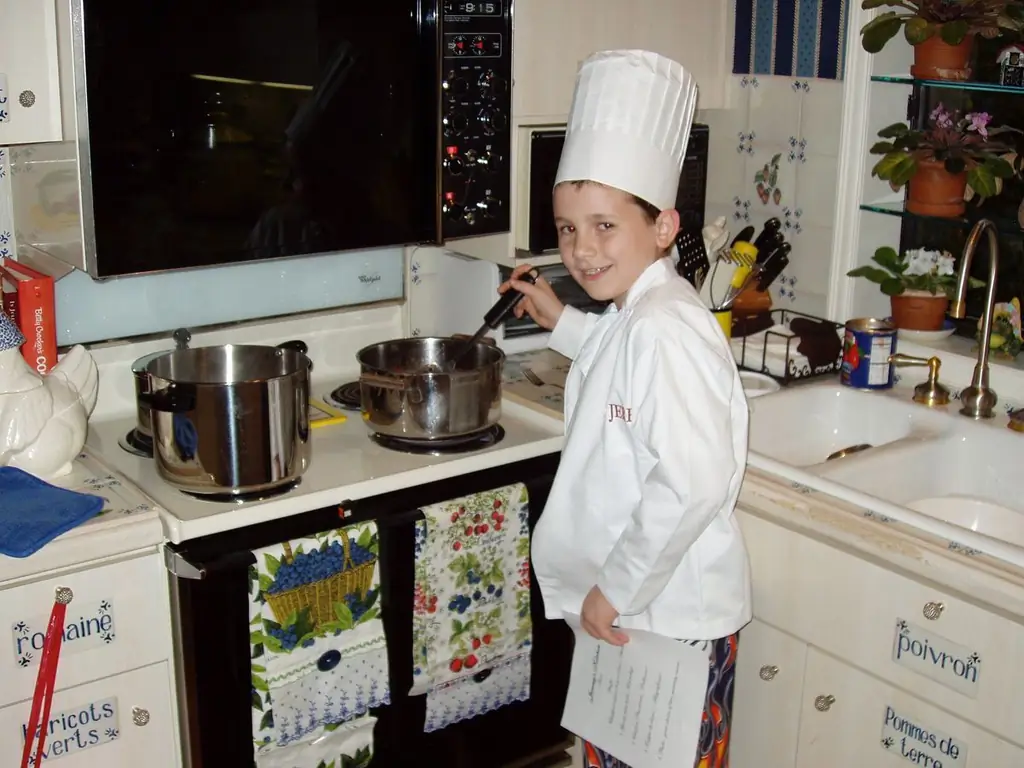 Ребенок у плиты в белом от шеф-повара