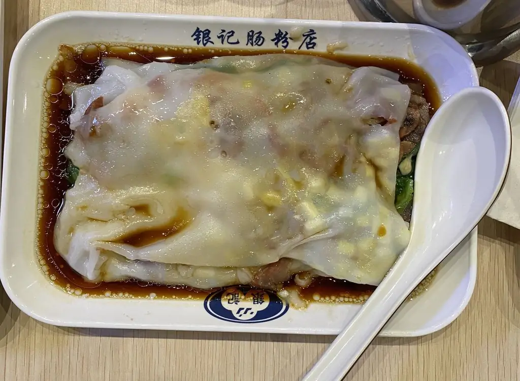 Рисовый рулет из свинины барбекю с зеленым луком лежит на белой тарелке с ложкой