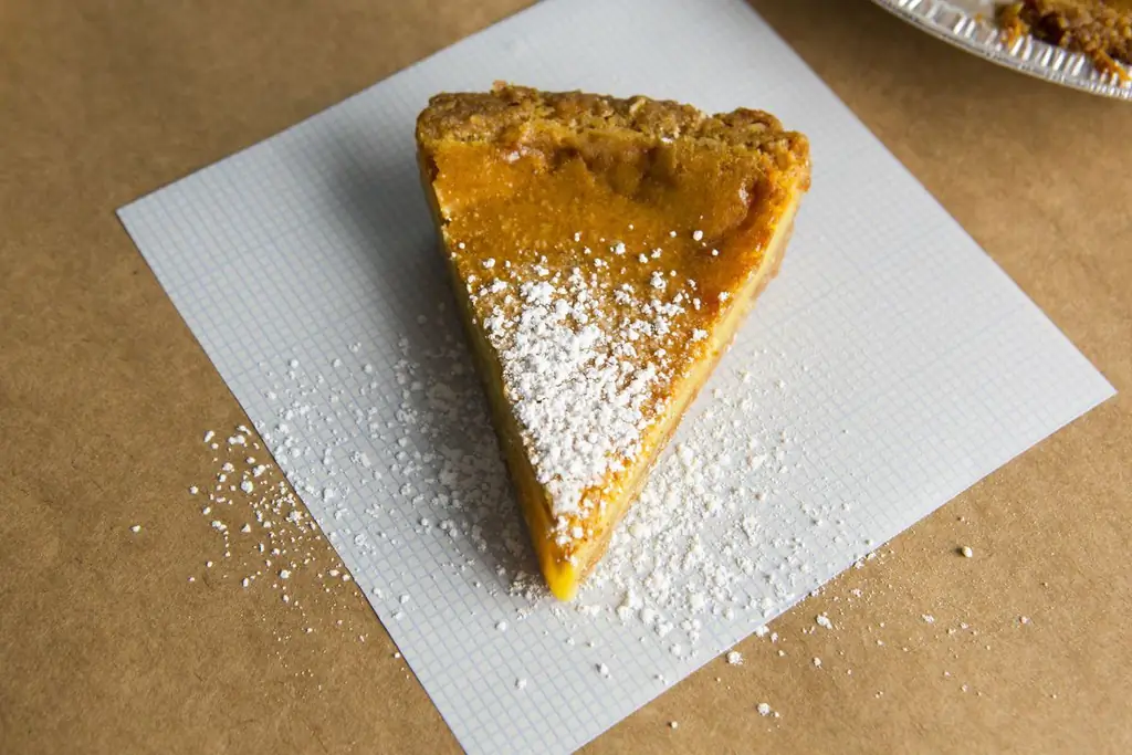 Кусочек пирога с сахарной пудрой на листе пергаментной бумаги