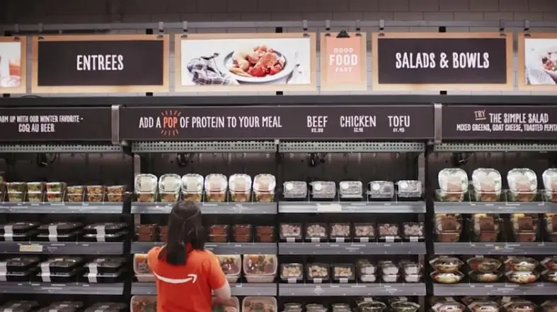 Сотрудник стоит перед витриной в магазине Amazon Go