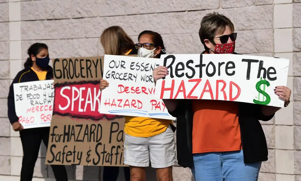 Четыре человека стоят снаружи с табличками. На одном написано «Восстановить опасность $»