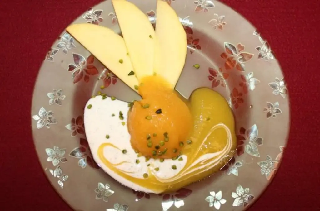 Сорбет из манго с йогуртово-ванильным соусом и соусом из манго, украшенный кусочками фисташек