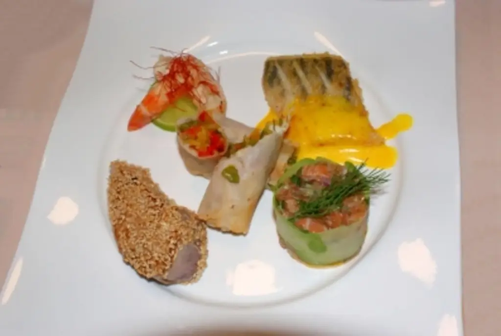 Рыбная вариация Тартар из лосося, тунец с лаймом, приготовленный в оливковом масле, филе судака, запеченное на коже, королевские креветки, овощной рулет на пене из шафрана