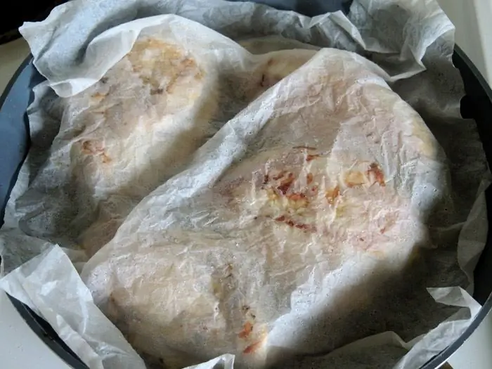 куриная грудка на сковороде, покрытая пергаментной бумагой куриная грудка на сковороде, покрытая пергаментной бумагой